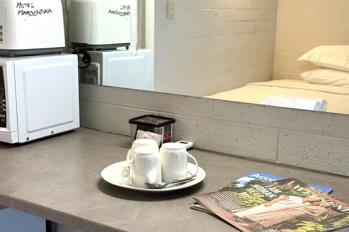 A kitchenette with a microwave, a coffee maker, and a tray with cups and a teapot.