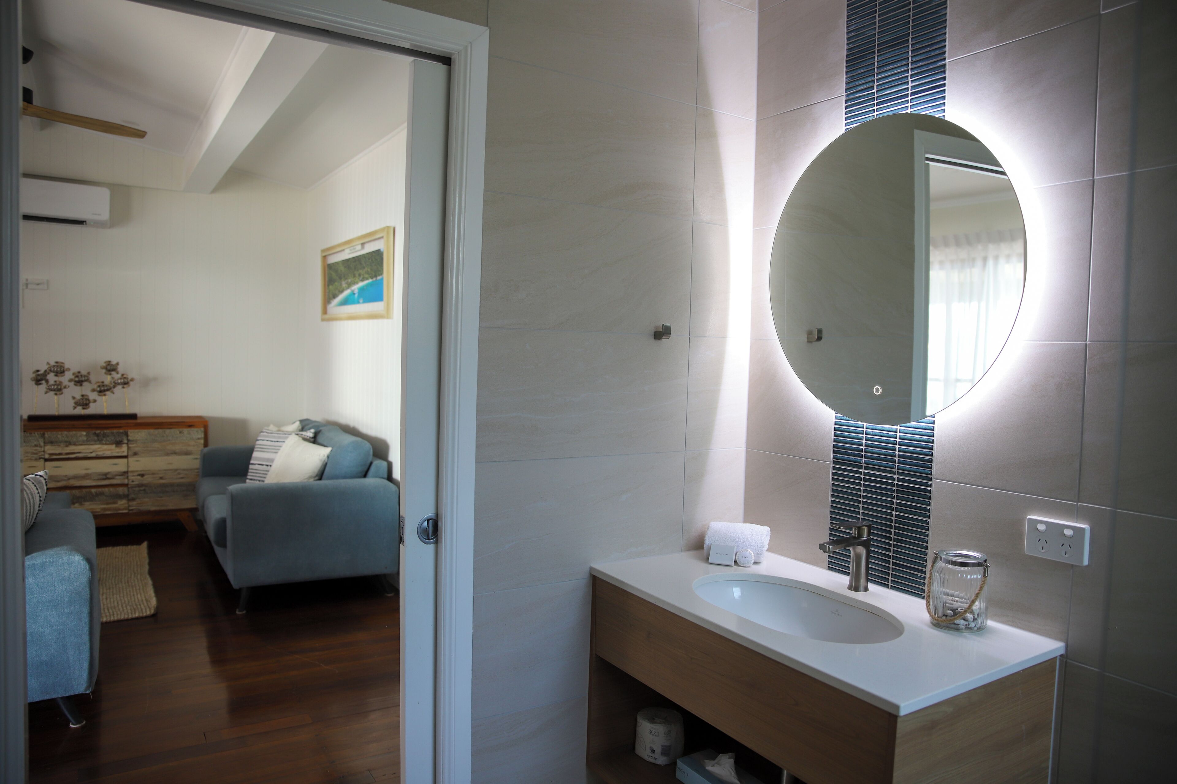 A modern bathroom with a large mirror, a sink, and a wooden vanity.