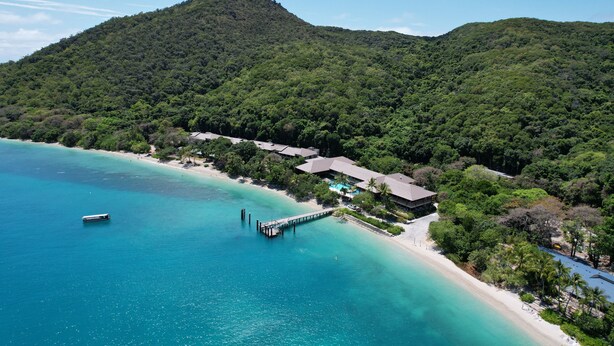 A coastal resort with a pier extending into turquoise waters, surrounded by lush greenery and a mountain backdrop. - Fitzroy Island Resort (Fitzroy Island)