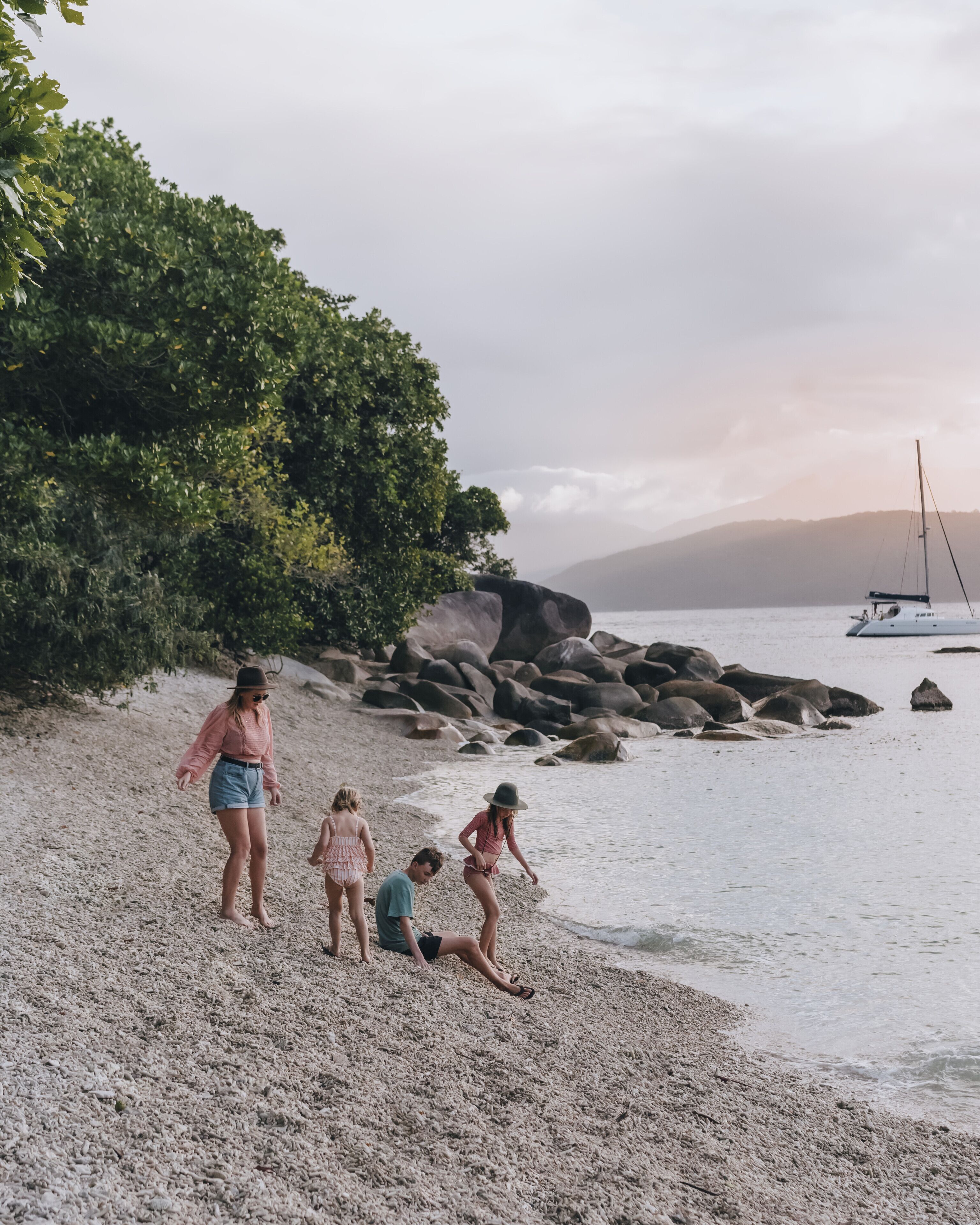 A beach scene with rocky terrain and a sailboat in the distance.