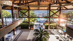 A covered outdoor area with a view of a pool and palm trees, featuring a wooden ceiling and seating areas. - Fitzroy Island Resort (Fitzroy Island)