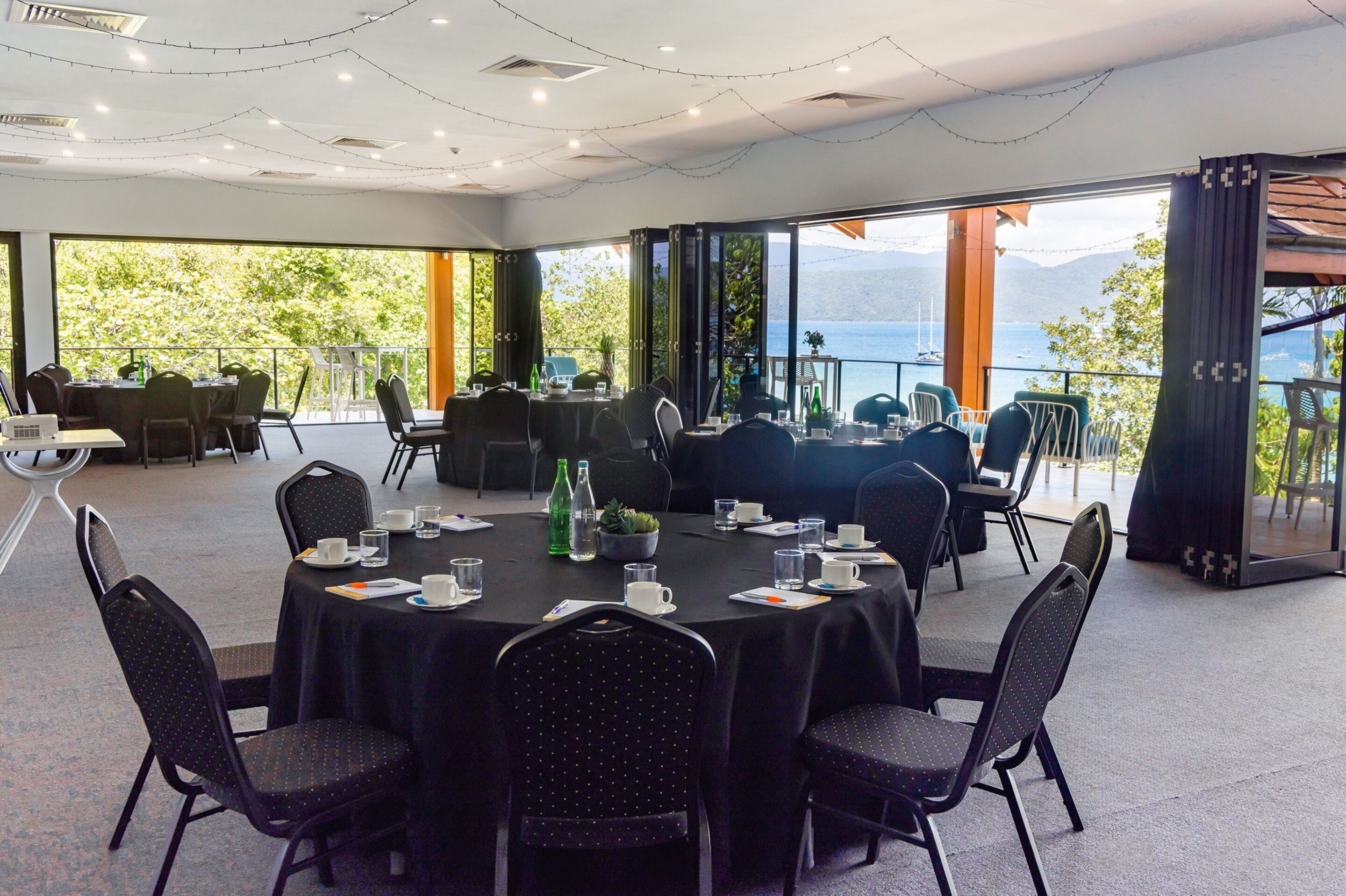 A conference room with round tables, chairs, and a view of a lake.