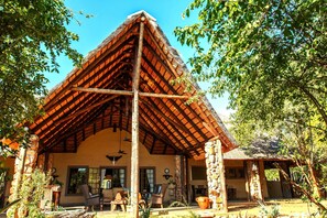 A rustic building with a thatched roof, stone pillars, and a covered porch area. - Shikwari Nature Reserve (Hoedspruit)