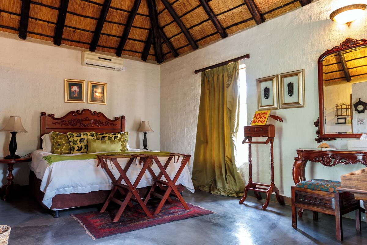 Un dormitorio con cama, mesitas de noche, espejo y ventana con cortinas.