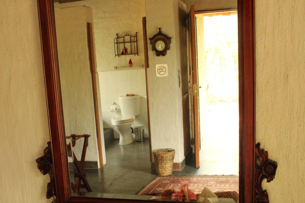 Una consola de madera con un espejo que refleja el interior de un baño.