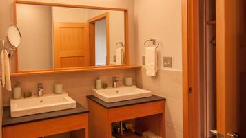 A bathroom with two sinks, a mirror, a towel rack, and a door.
