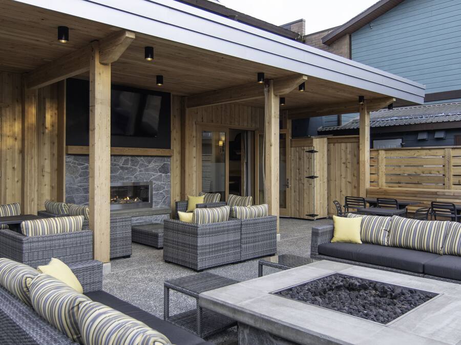 An outdoor patio area with wicker furniture, a stone fireplace, and a covered seating area.