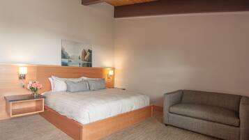 A bedroom with a bed, bedside tables, a nightstand, a sofa, and a painting on the wall.