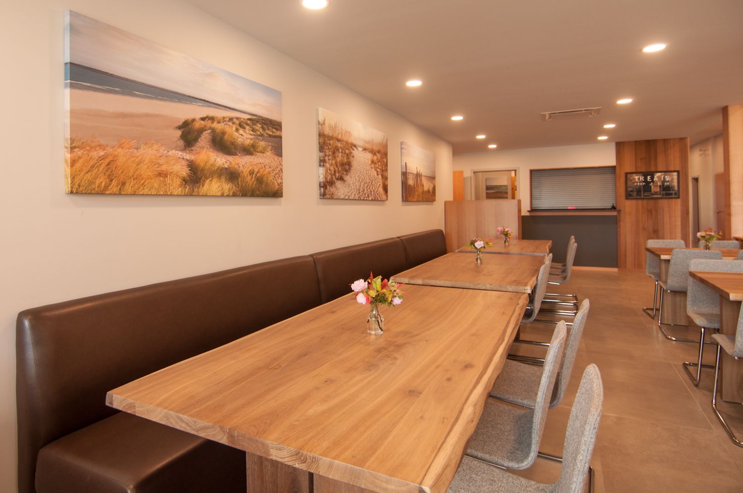 A conference room with long tables and benches, decorated with floral centerpieces.