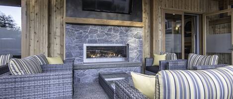 An outdoor seating area with wicker furniture and a stone fireplace.