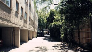 A narrow alleyway flanked by buildings with brick facades and a wooden fence on one side. - H&D Apartments (St Kilda)