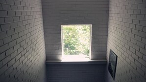 A narrow stairwell with white brick walls and a window at the top. - H&D Apartments (St Kilda)