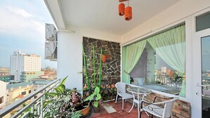 Een balkon met een stenen muur, plantenpotten, een tafel en stoelen.