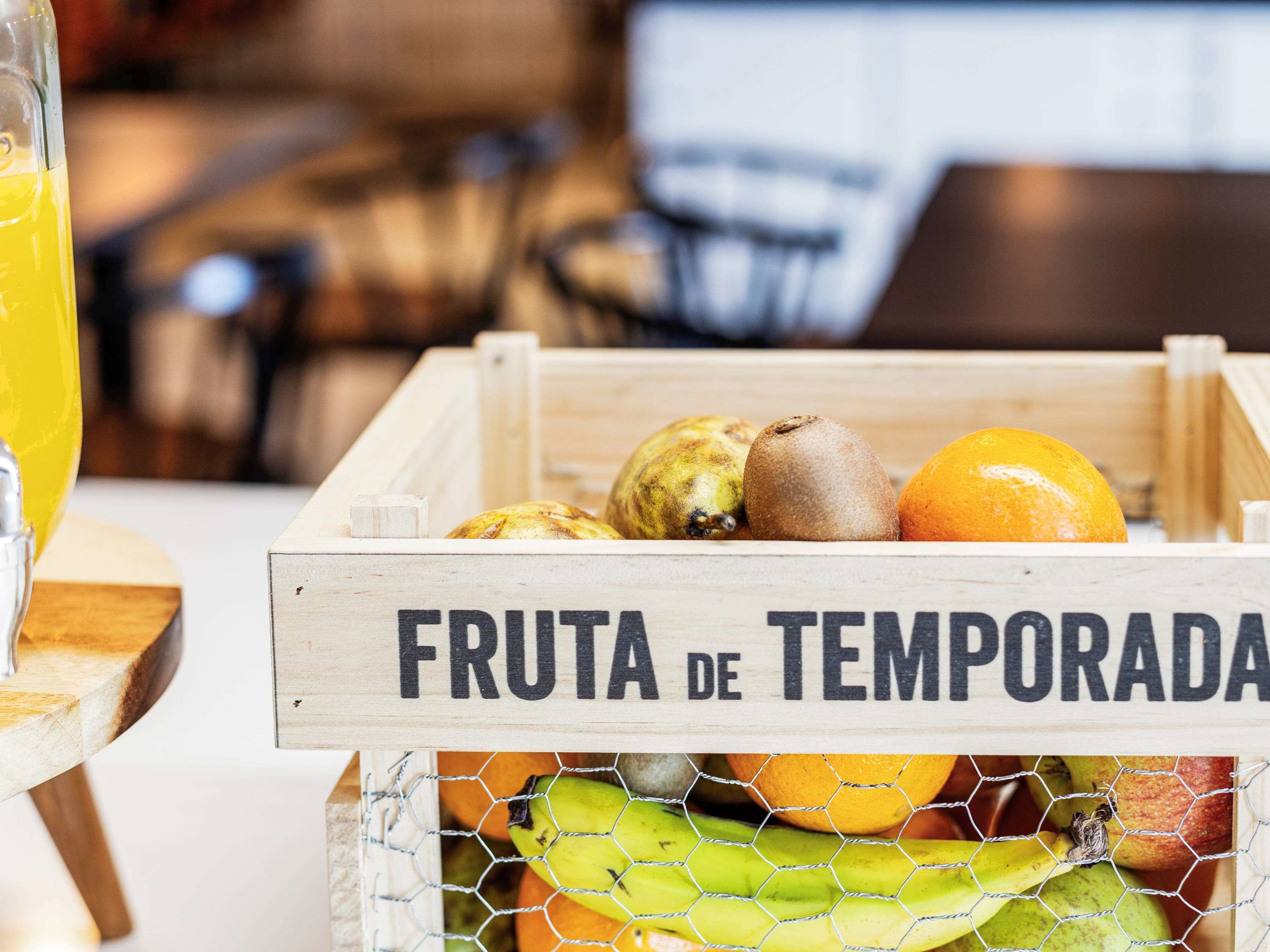 A wooden crate labeled "FRUTA DE TEMPORADA" containing various fruits.