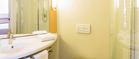 Un baño con lavamanos, espejo, toallero, ducha e inodoro.