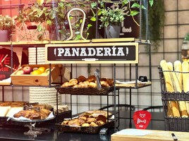 Una vitrina de pastelería con pasteles, pan y frutas.
