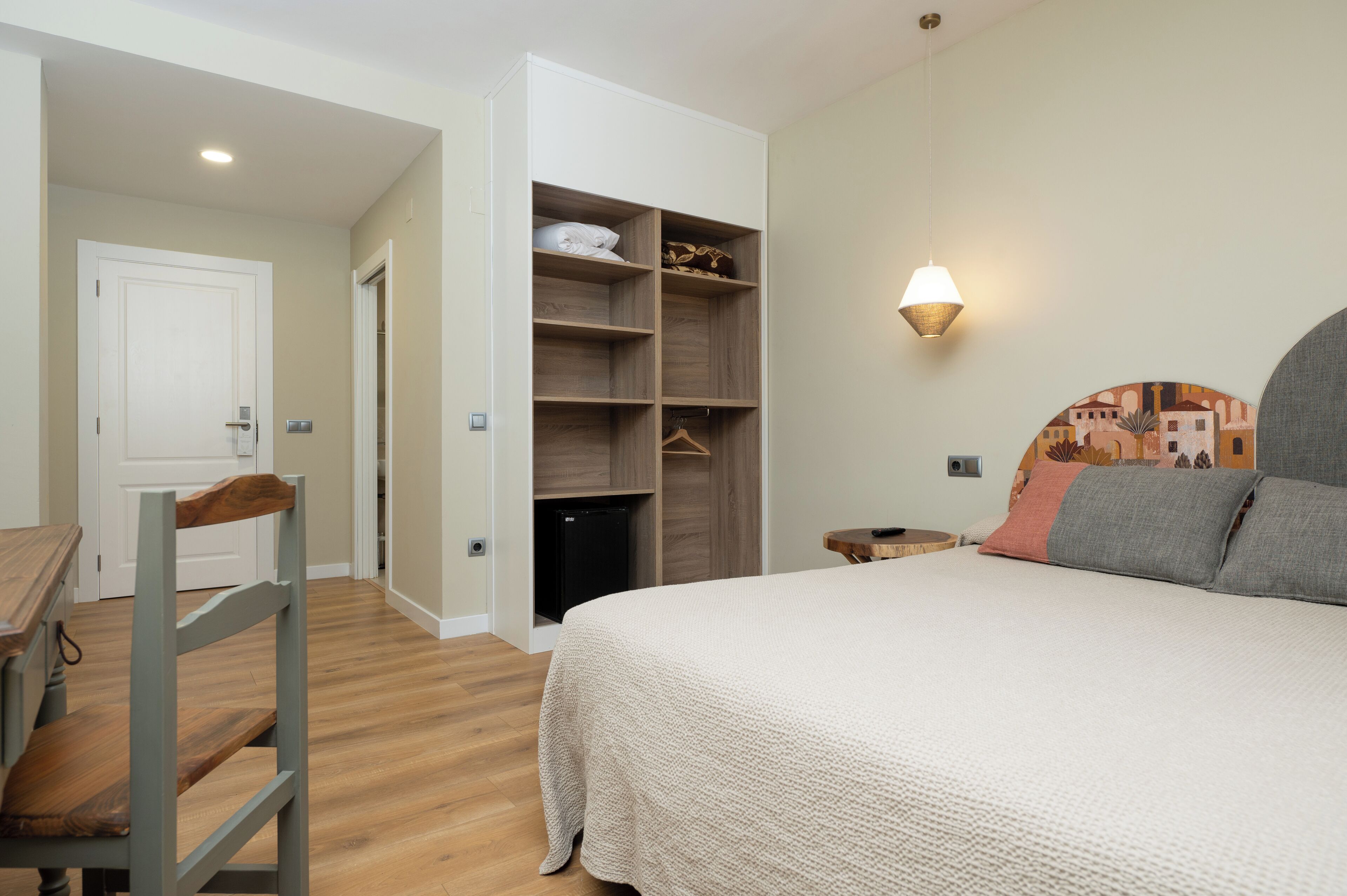 Ein Schlafzimmer mit einem Bett, einem Holzstuhl, einem Kleiderschrank und einem kleinen Tisch.