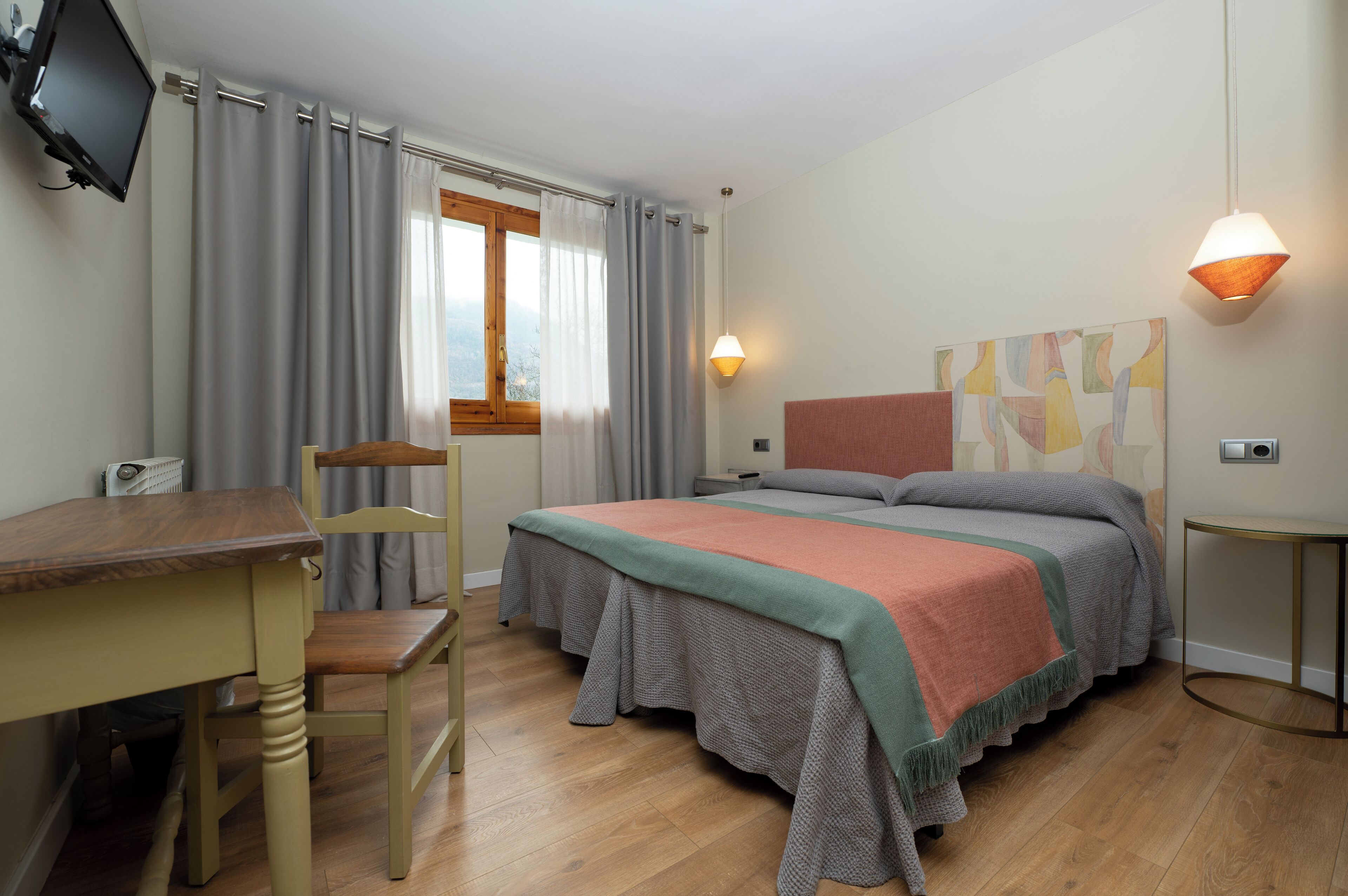 Un dormitorio con cama, escritorio, silla y televisor.
