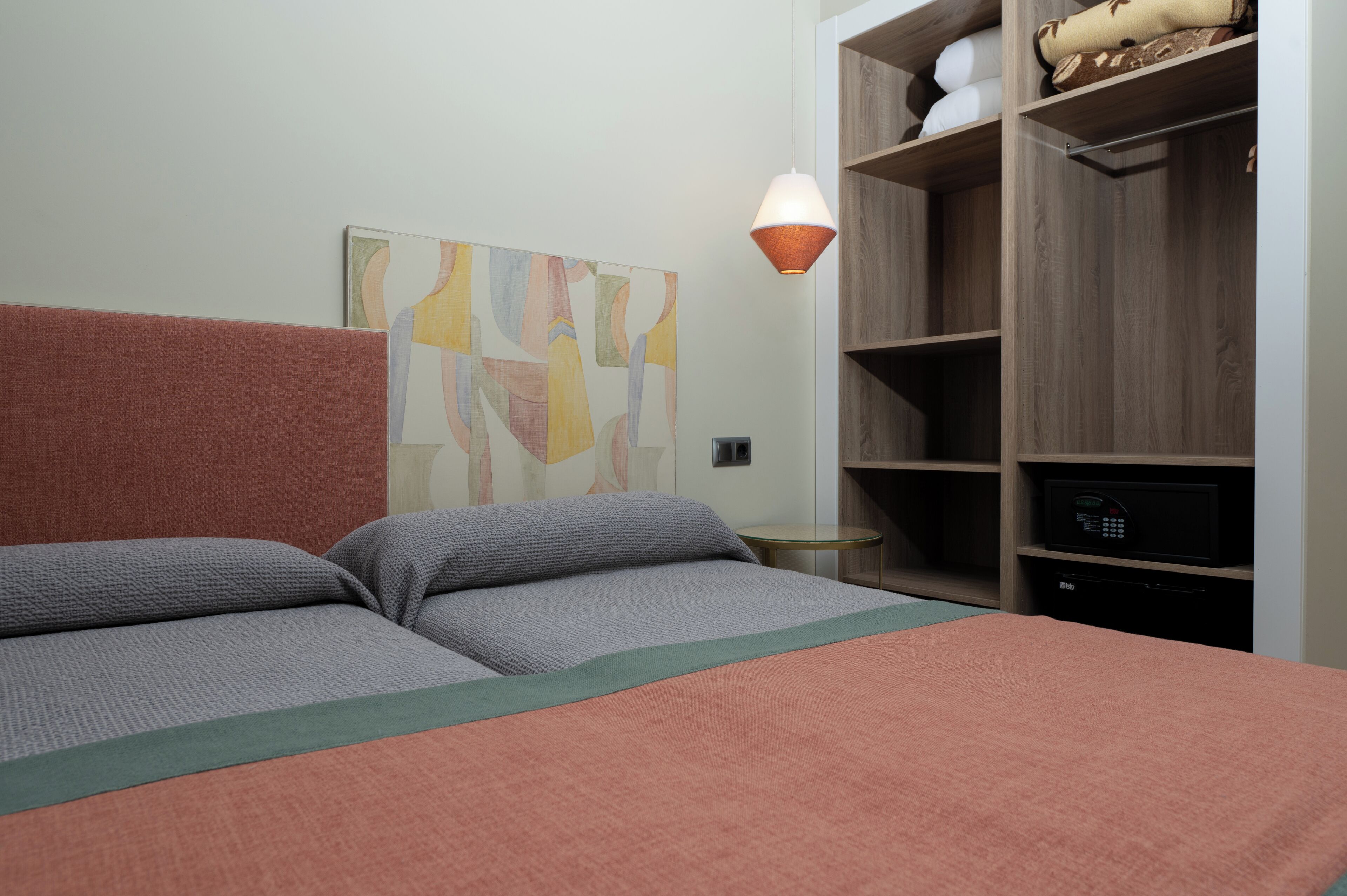 Une chambre à coucher comprenant un lit, une œuvre d’art murale, une lampe et une armoire intégrée.