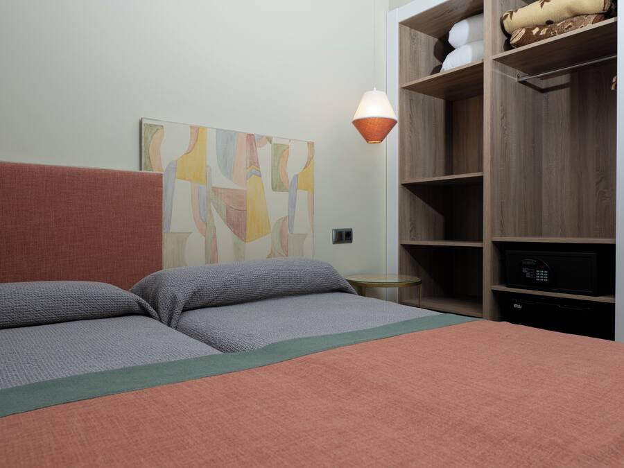 Un dormitorio con cama, una obra de arte en la pared, una lámpara y un armario empotrado.