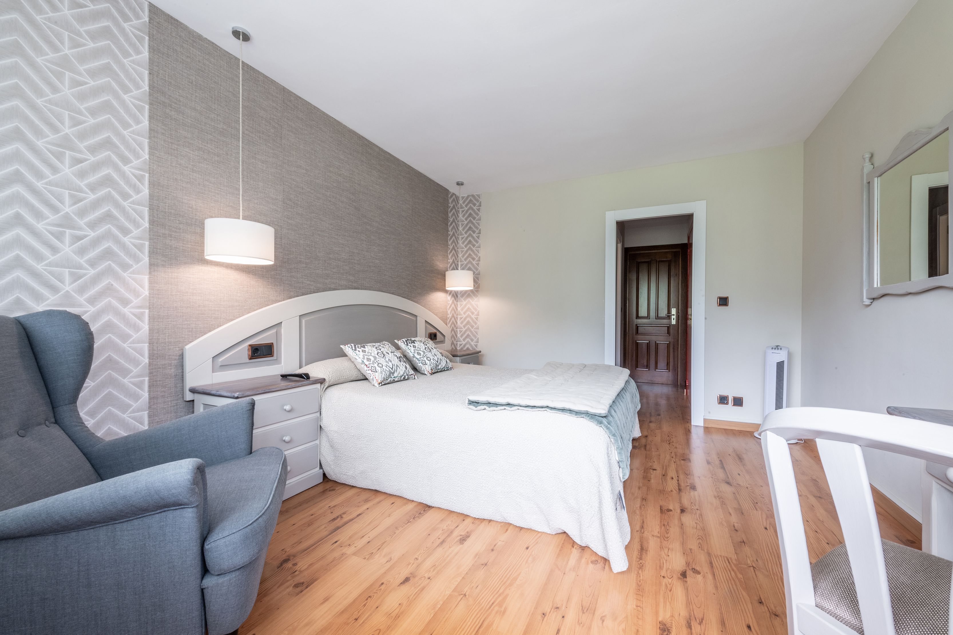 Une chambre à coucher avec un lit, une table de chevet, une lampe et une chaise.