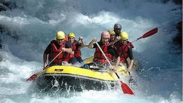Un grup de persones en un raft groc navegant per un riu amb rapids.