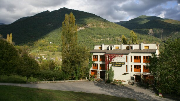 Un hotel con una estructura de dos pisos, una entrada visible y un cartel que indica que es un hotel y restaurante.