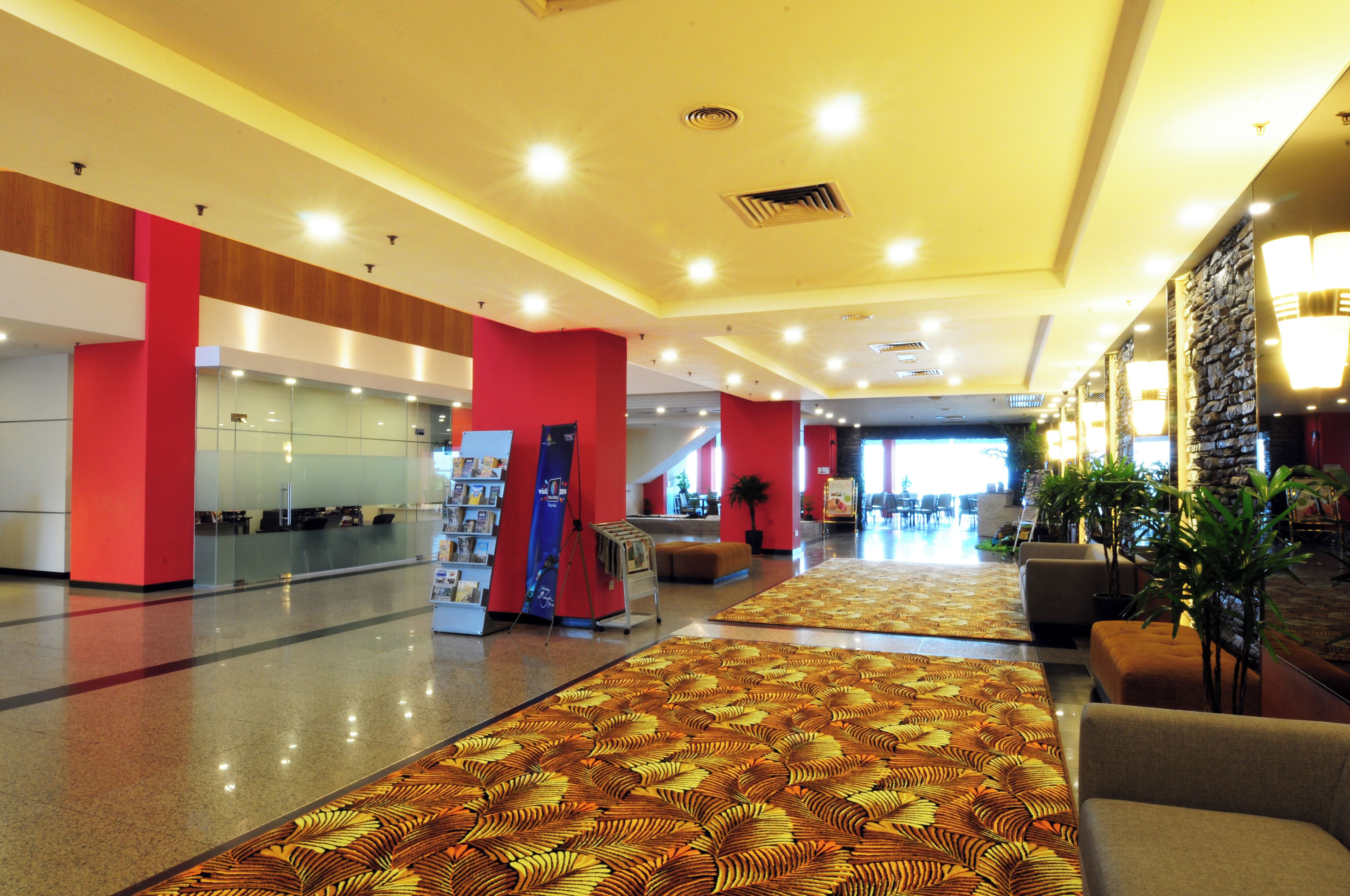 A spacious lobby with a patterned carpet, a reception desk, and a seating area with a sofa.