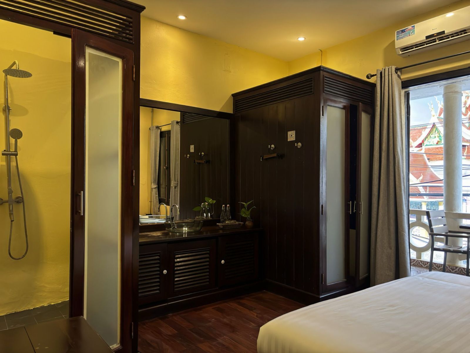 Camera d'albergo con un letto grande, cabina armadio, bagno con doccia e vista su un edificio tradizionale.