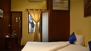 Un dormitorio con cama, ventana con cortinas, mesita de noche y aire acondicionado instalado en la pared.