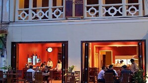 Un edificio de dos pisos con un restaurante en la planta baja. Cuenta con áreas de estar al aire libre, con mesas y sillas.