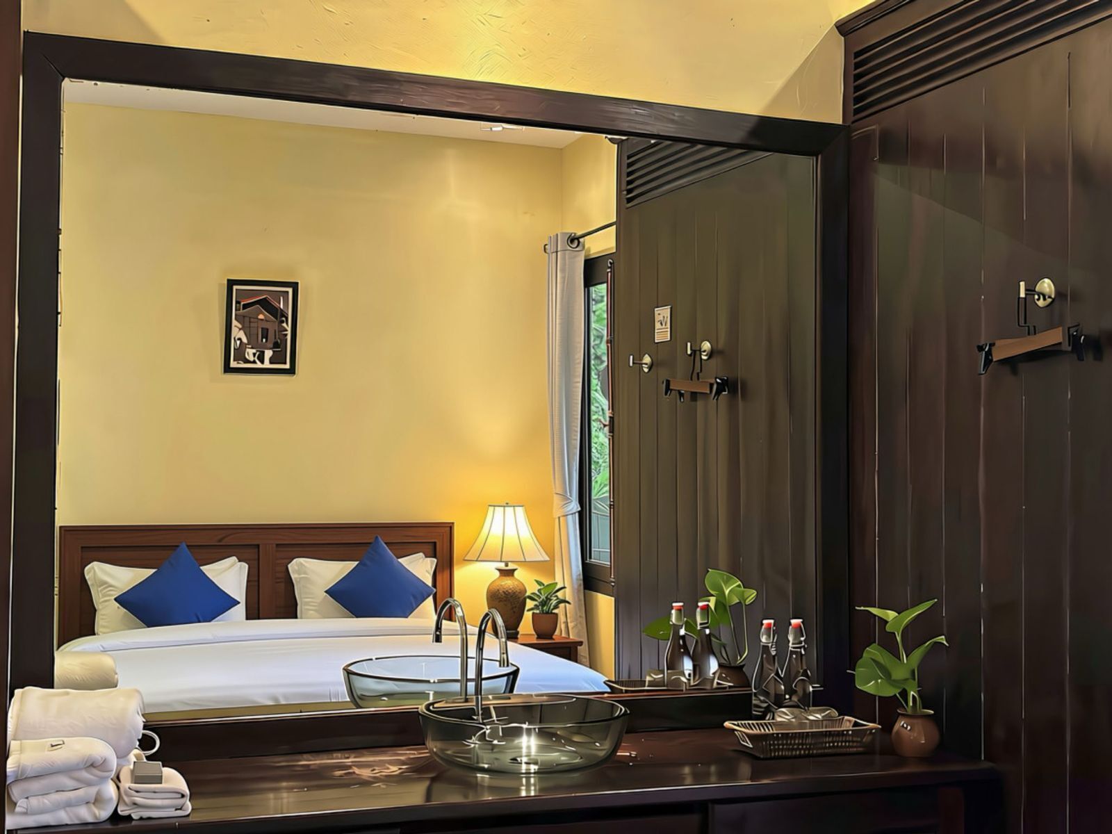 Habitación de hotel con cama, mesita de noche con lámpara, espejo y armario.
