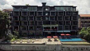 Un hotel de varios pisos con zona de piscina, mobiliario exterior y vistas al río.