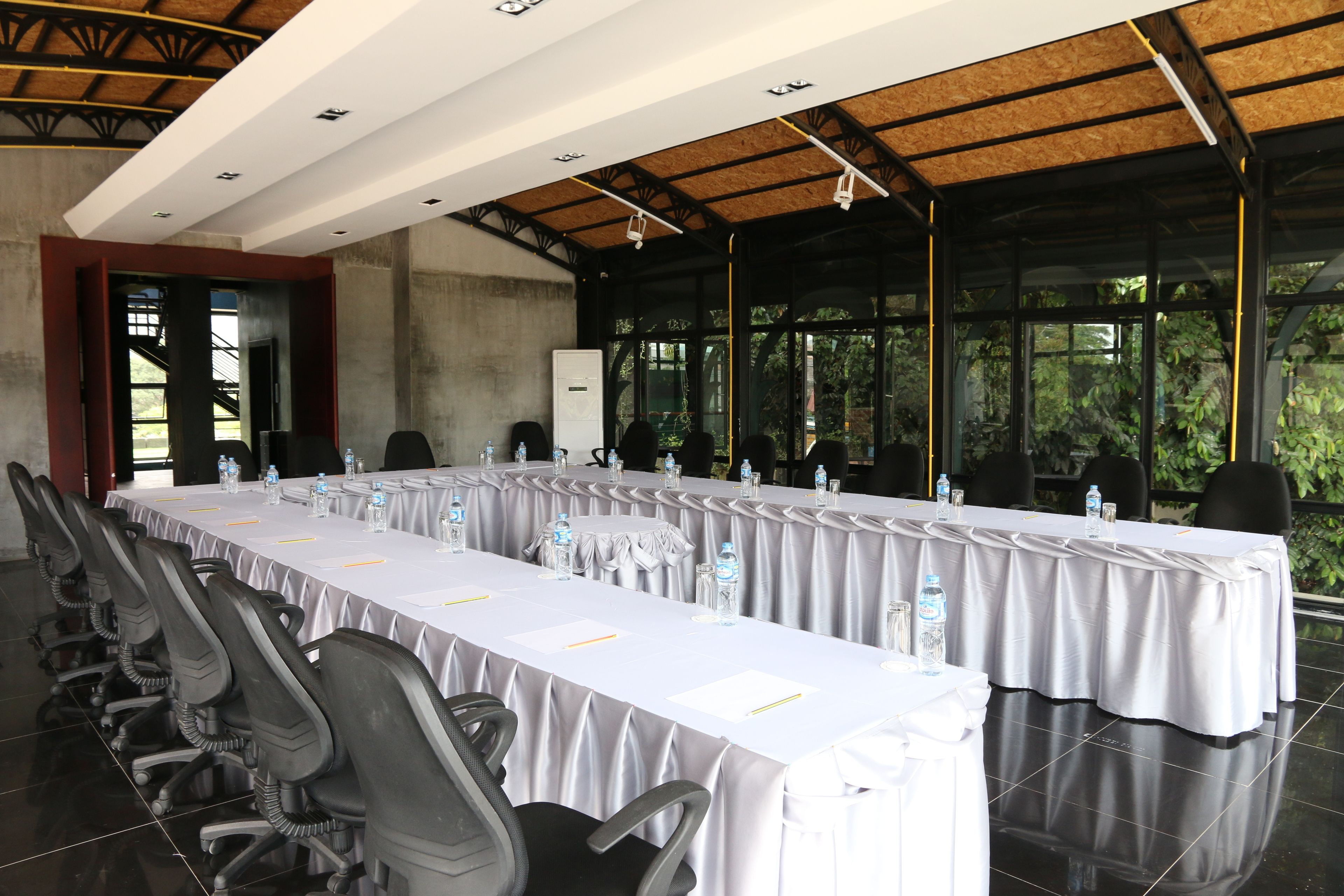 Une salle de conférence avec une longue table, des chaises et des bouteilles d’eau.