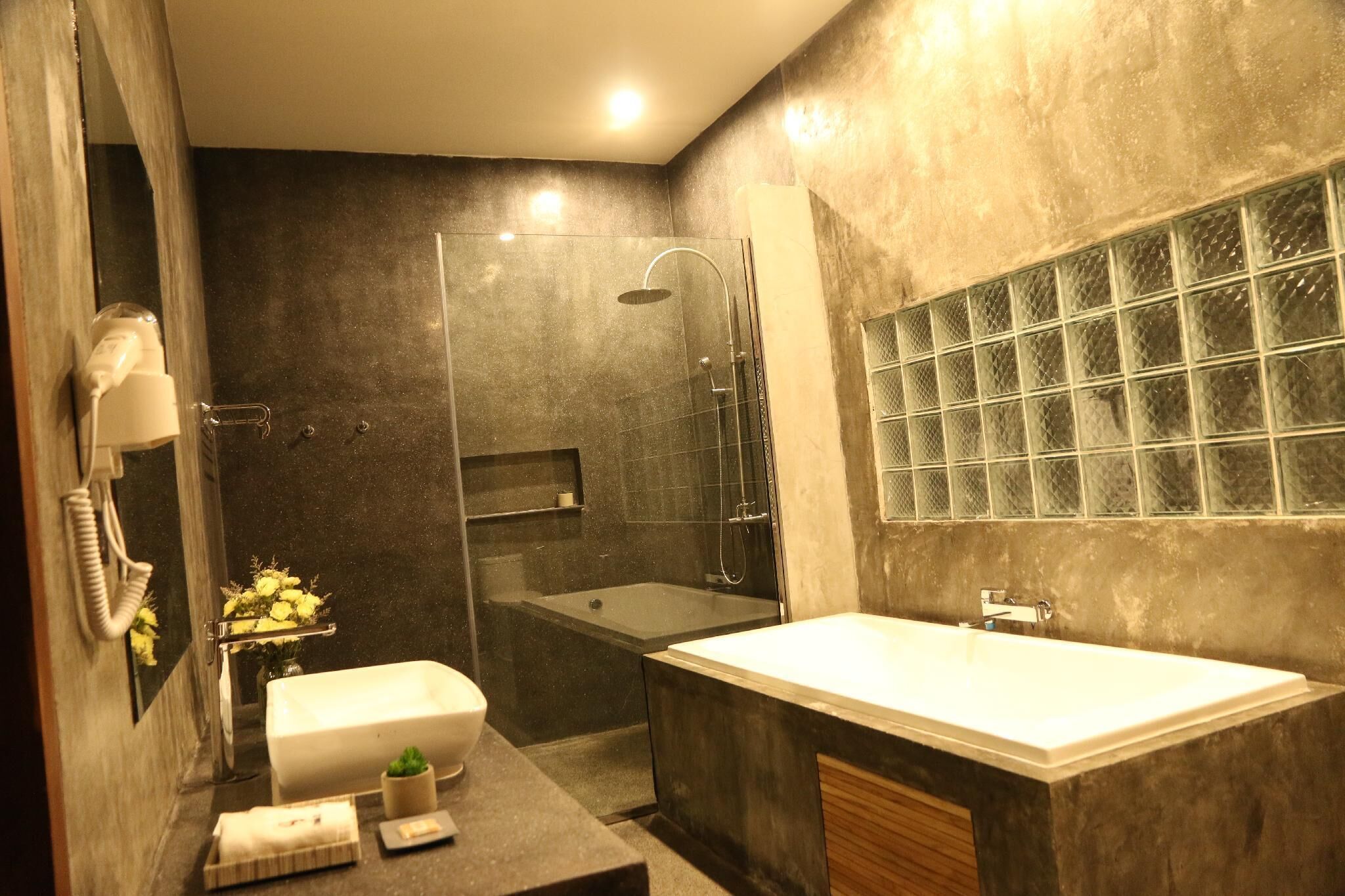 Un baño moderno con una bañera grande, ducha con mampara de vidrio y tocador con espejo.