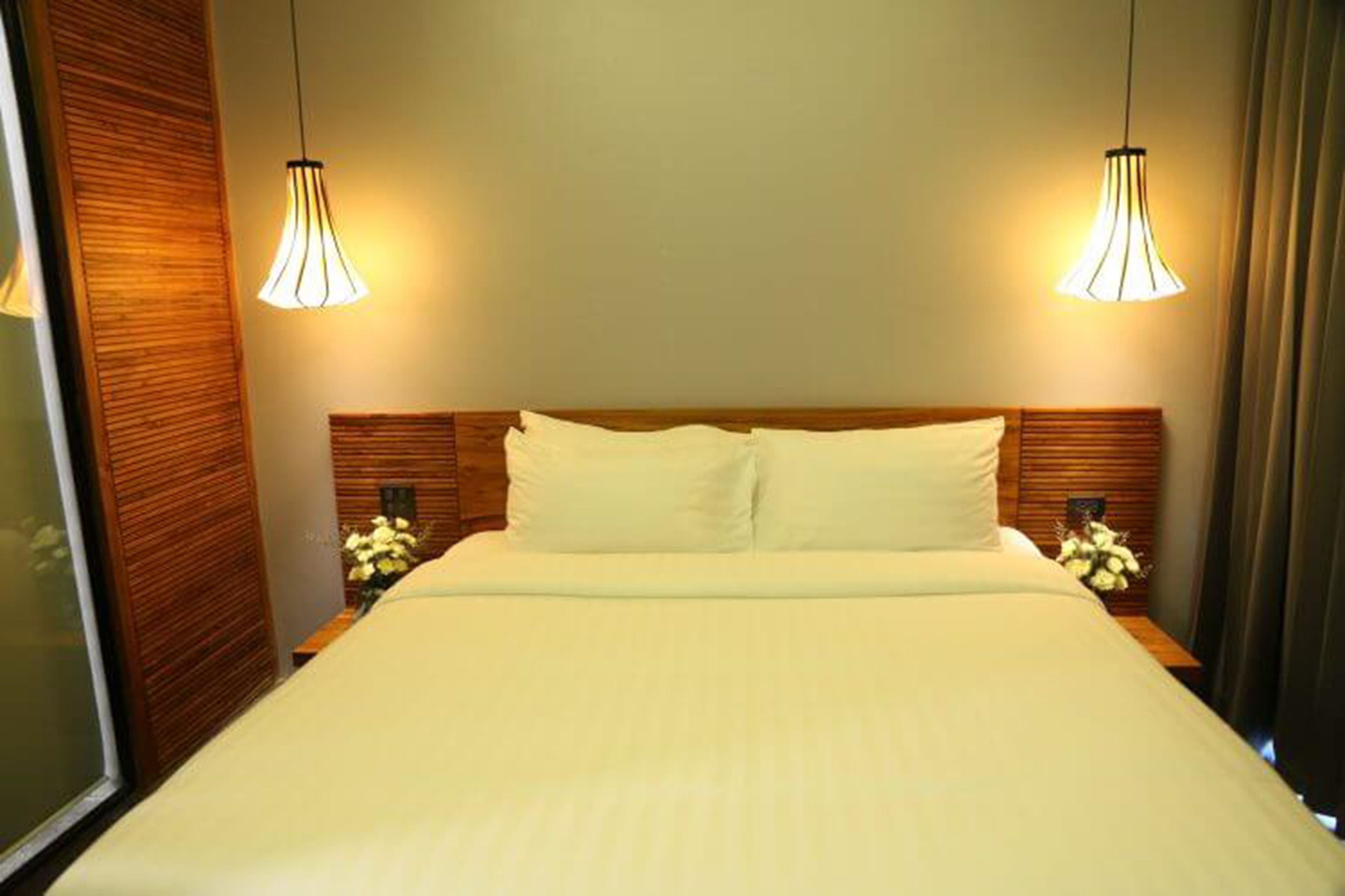 A hotel room with a large bed, two bedside tables with lamps, and a wooden headboard.