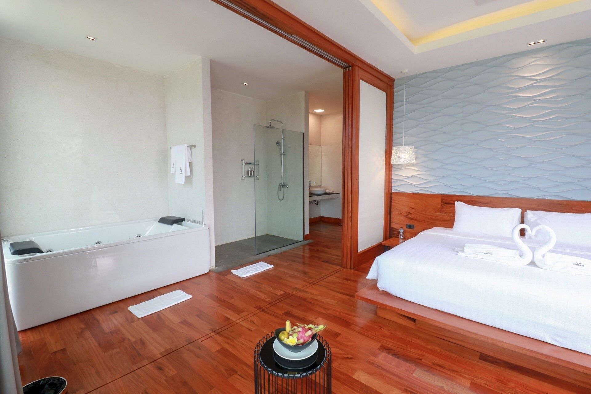 A hotel room with a large bed, a separate bathroom, and a wooden floor.