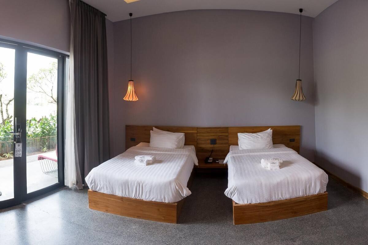 Et hotelværelse med to senge, et stort vindue og en dør til udendørs.