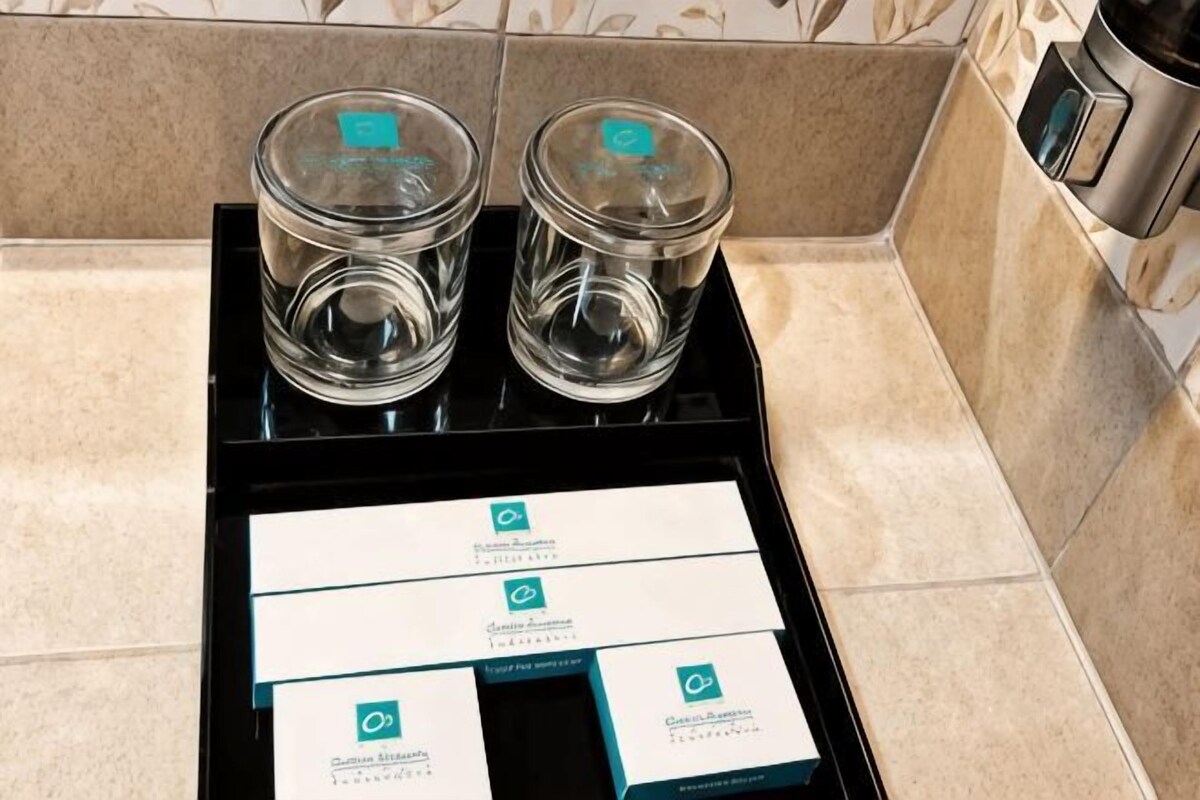Un plat amb dos vasos de cristall i un estri de targetes de visita amb el logotip de la marca.