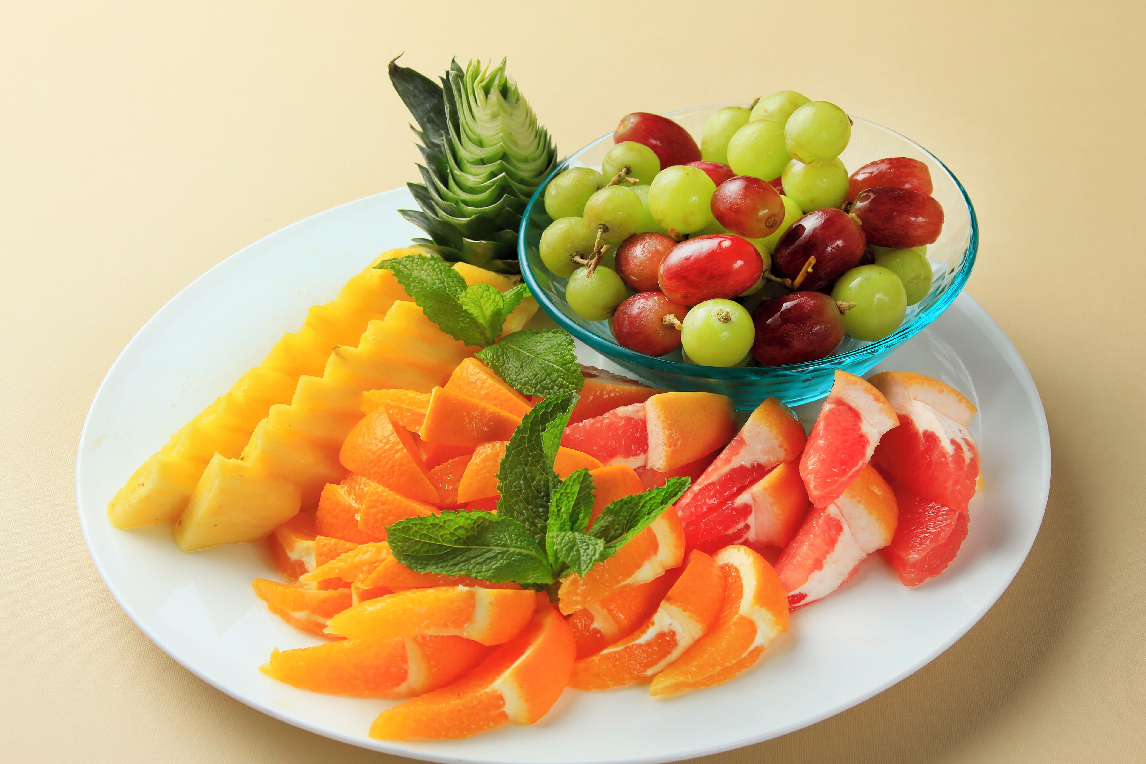 A plate with sliced fruits and a bowl of grapes.