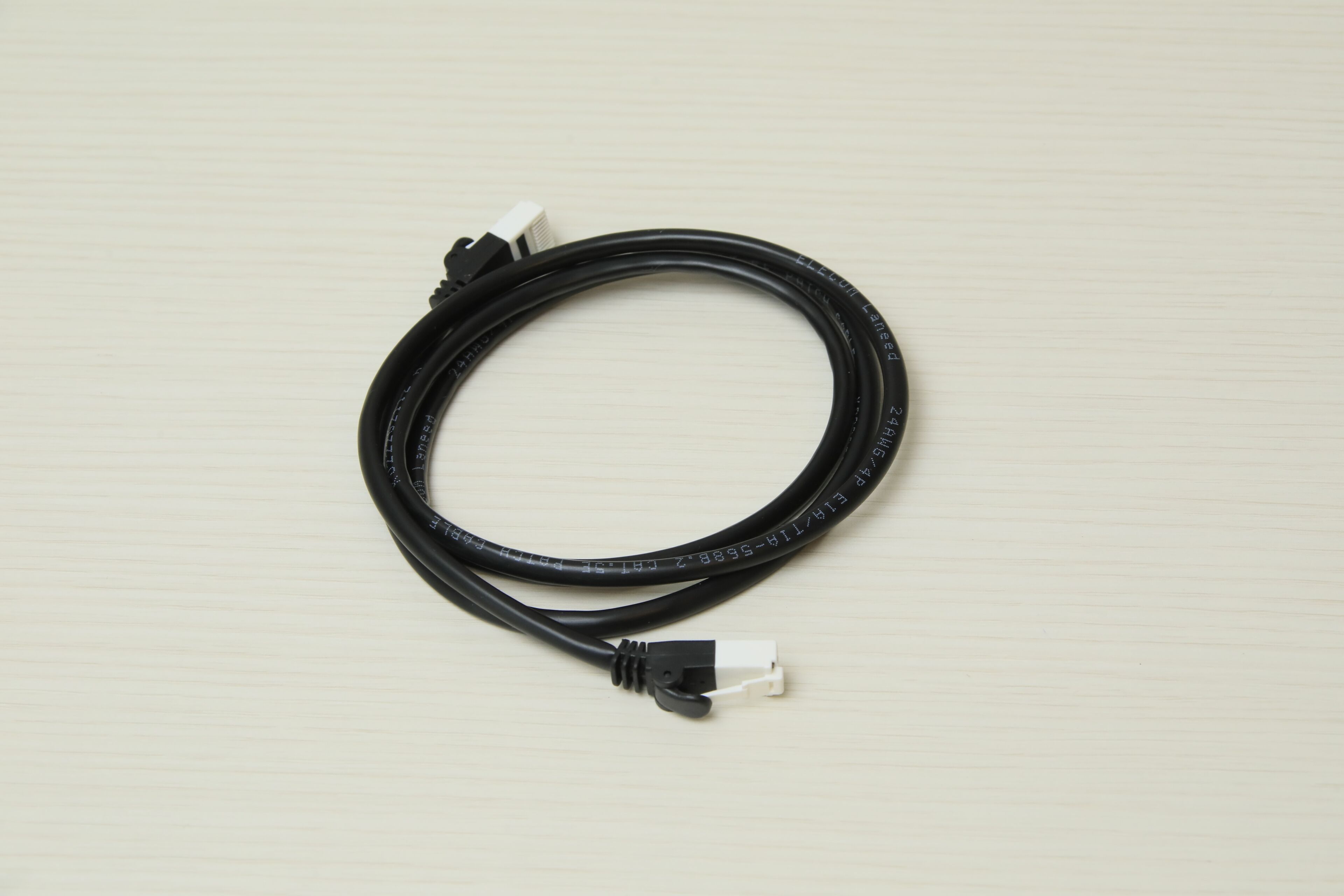 A black cable with a white connector on a light-colored surface.