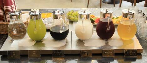 A beverage station with various drinks and a fruit tray.