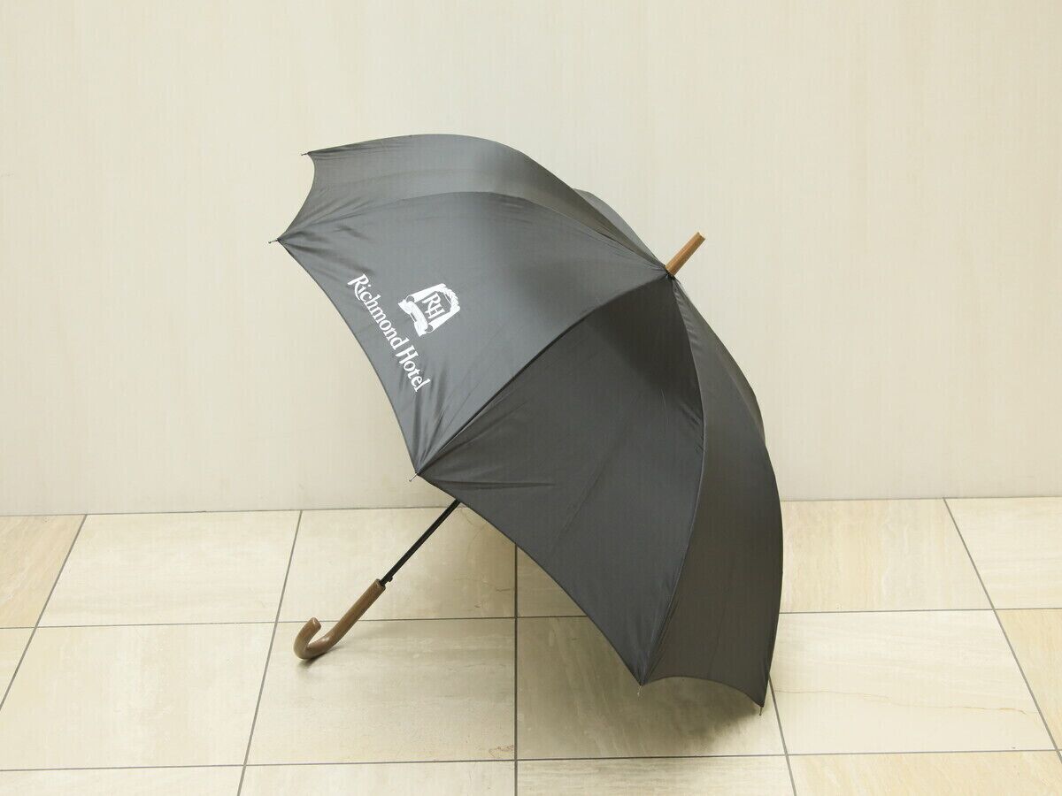 A black umbrella with a logo on it, lying on a tiled floor.