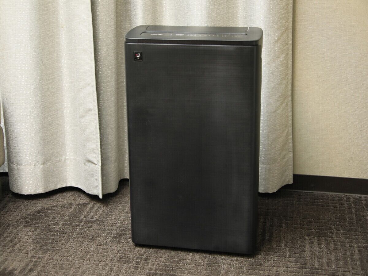 A black, rectangular, metallic object with a control panel on top, standing on a carpeted floor.