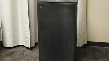 A black, rectangular, metallic object with a control panel on top, standing on a carpeted floor.