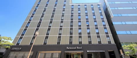 Un hotel moderno y alto, con una entrada llamativa y un cartel con el nombre.