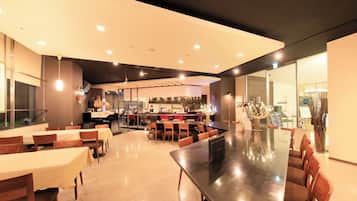 Un restaurante moderno con una mesa común alargada, mesas individuales y una zona de bar.