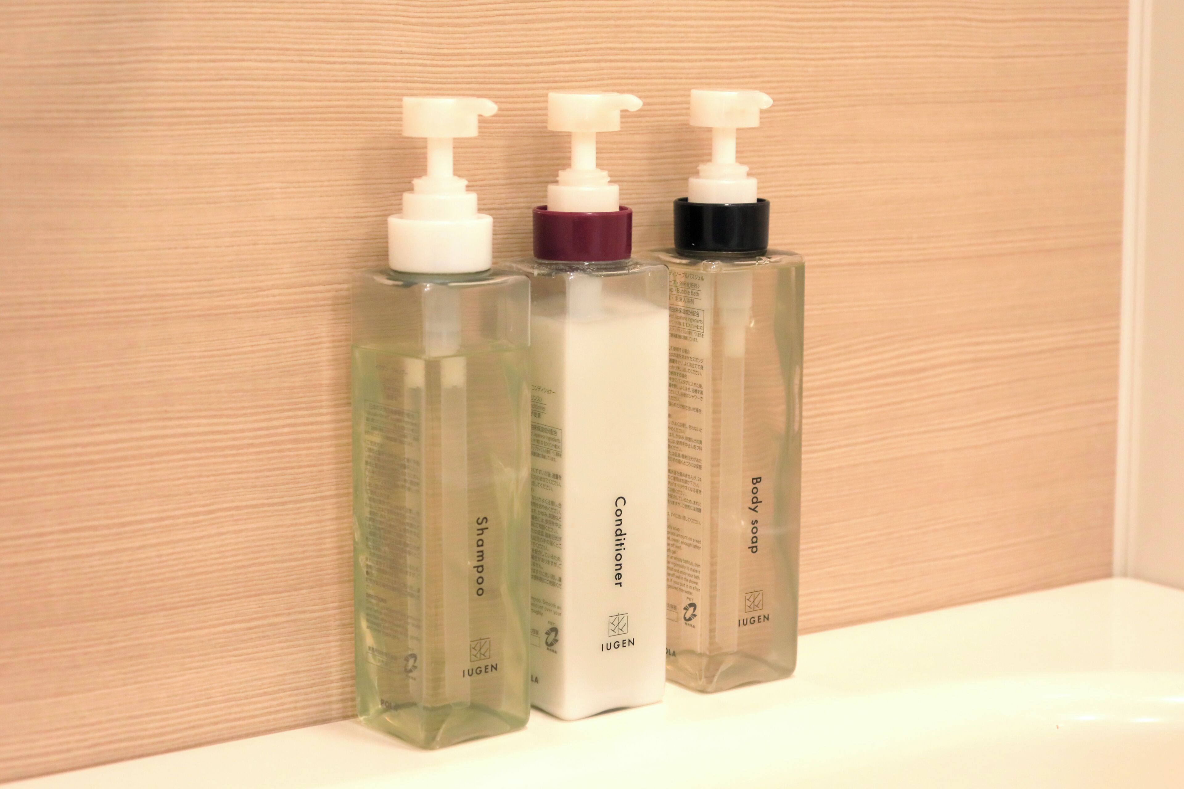 Trois bouteilles de produits de soins personnels de la marque Iugen, posées sur une surface blanche.
