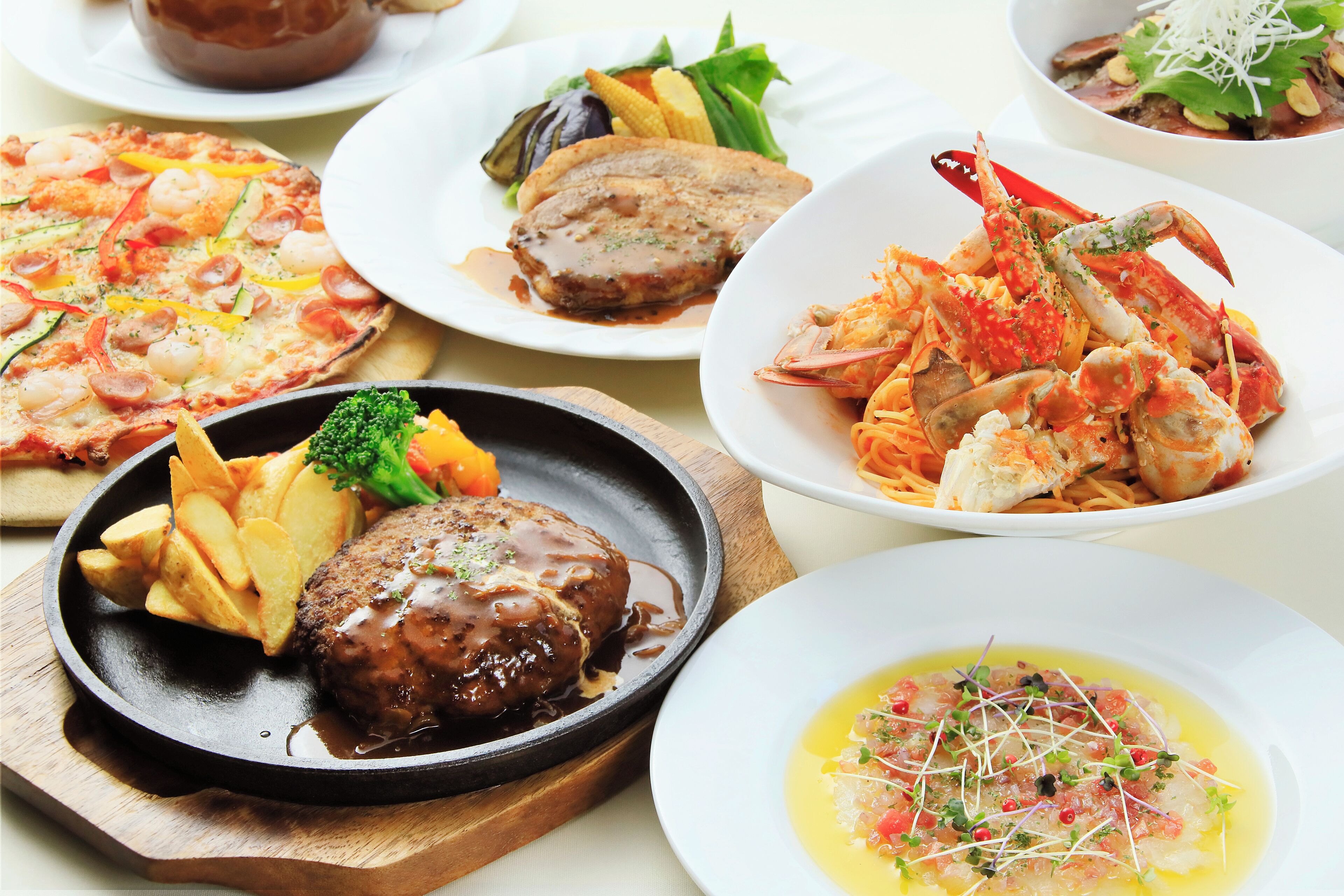 Variedad de platos, incluyendo pizza, mariscos y un bistec con salsa.