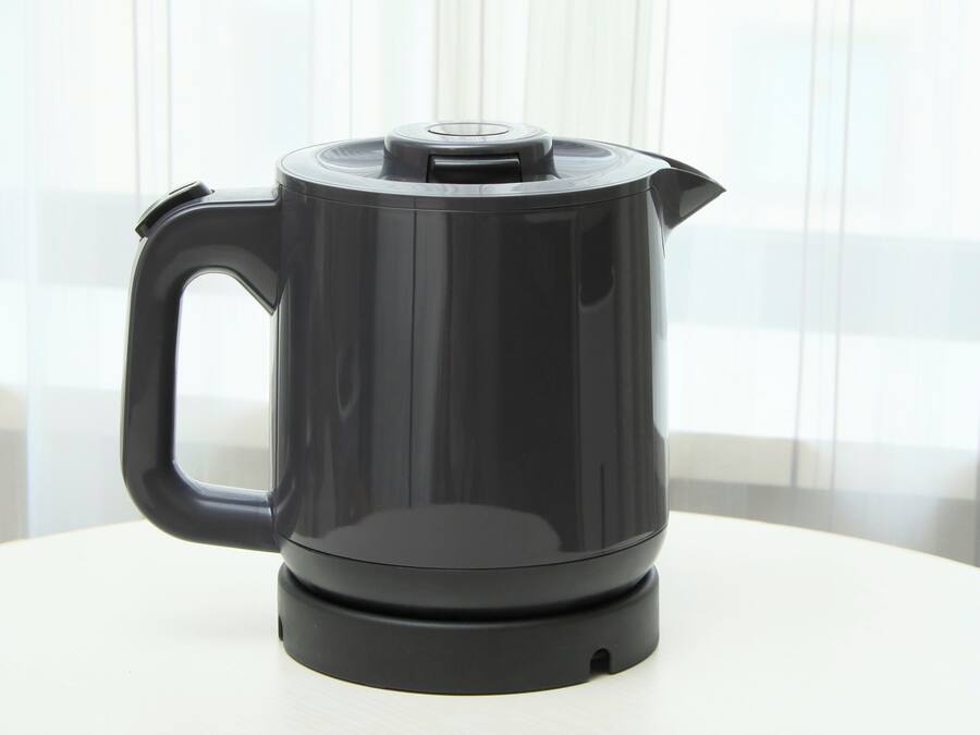 A black electric kettle on a white table.